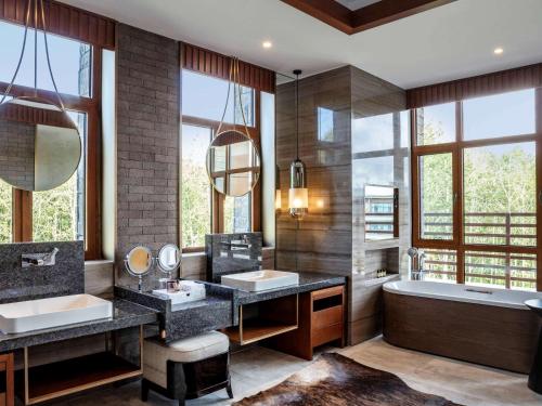 抚松县长白山吉视传媒铂尔曼度假酒店的一间带两个盥洗盆和浴缸的浴室以及窗户。