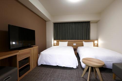 御殿场市Dormy Inn Express Fujisan Gotemba的酒店客房设有两张床和一台平面电视。