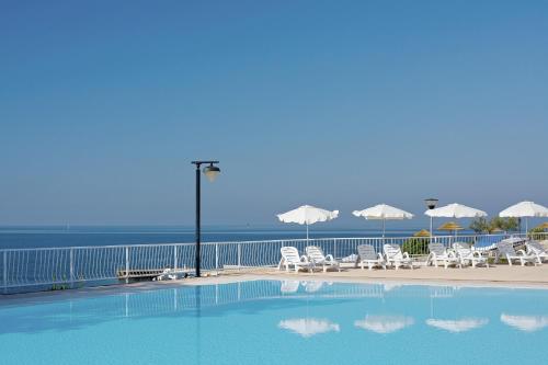 波雷奇FKK Solaris Camping Resort by Valamar的毗邻大海的带椅子和遮阳伞的游泳池