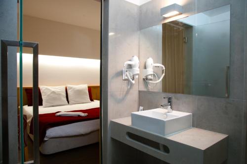 法蒂玛Casa Avé Maria的一间带水槽和镜子的浴室以及一张床