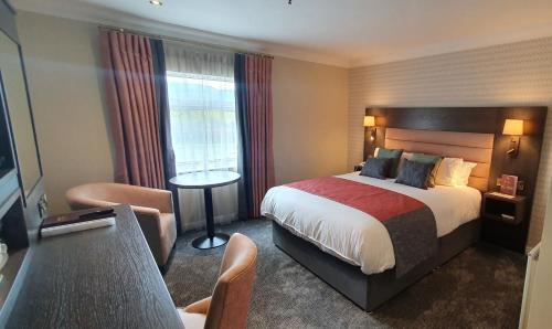 纽卡斯尔Burrendale Hotel Country Club & Spa的酒店客房带一张大床和一把椅子