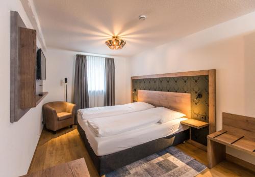 海利肯施塔特海力根思塔德尔霍夫酒店-餐厅的一间卧室配有一张大床和一把椅子