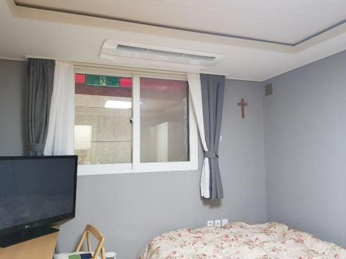 首尔Gyeongbokgung Palace Seochon Christian Home - Foreigner Only的一间卧室设有窗户、一张床和一台电视机