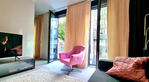 坦佩雷Uusi, avara, saunallinen keskustakaksio的客厅配有粉红色的椅子和大窗户