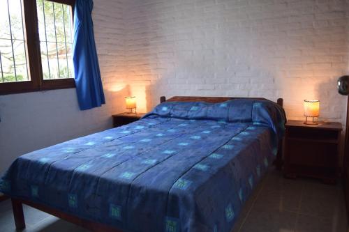 拉帕洛马Bungalows Costa Esmeralda的一间卧室配有一张带两盏灯的蓝色床。