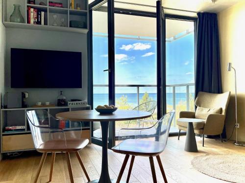 梅尔诺Tuż przy plaży - nowoczesny apartament z tarasem i pięknym widokiem na Bałtyk的客厅配有桌椅和电视。