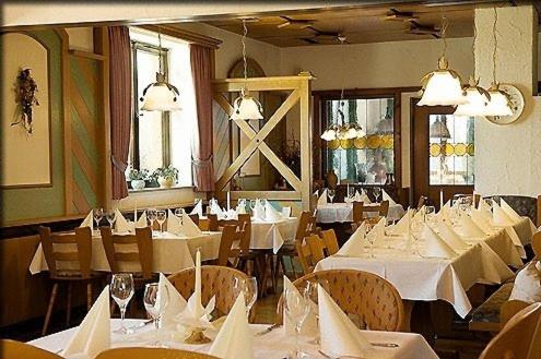 林登贝格拜耶里斯彻酒店的一间设有白色桌椅的用餐室
