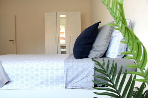 卢加诺Cozy apartment with Free Parking & close to Lake的一张带蓝色和白色枕头的床和植物