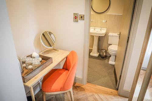 FlookburghHope and Anchor的浴室设有梳妆台、镜子和橙色椅子