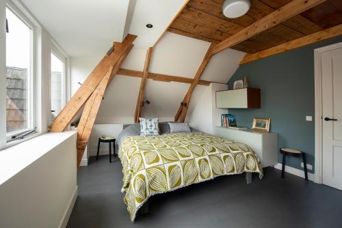 LangweerSchitterend appartement in dorpsstraat Langweer!的一间带一张床的卧室,位于带木制天花板的房间内