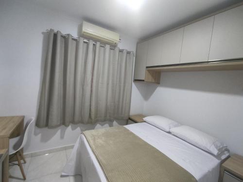 伊瓜苏Iguaçu Hospedagem的一间卧室配有一张床、一张书桌和一个窗户。