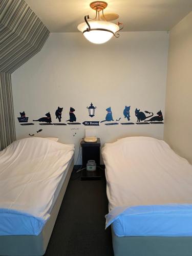 东京御宿心地经济型酒店的墙上有鸟的房间的两张床