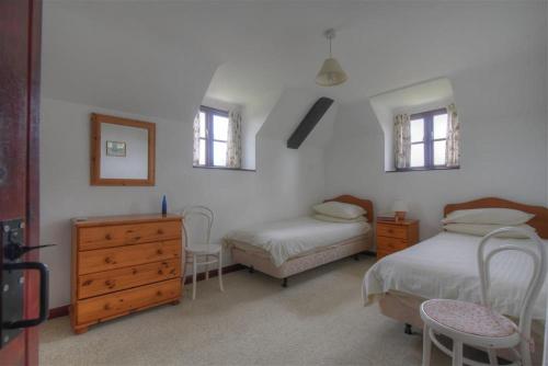 MusburyRose Cottage的一间卧室设有两张床、一个梳妆台和两个窗户。