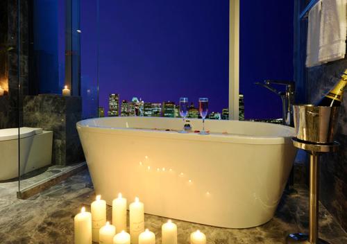 成都榛悦隆堡成都酒店的浴室配有带蜡烛和酒杯的浴缸。