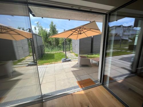 滨湖新锡德尔25h SPA-Residenz BEST SLEEP privat Garden & POOLs的开放式玻璃门,带雨伞的庭院