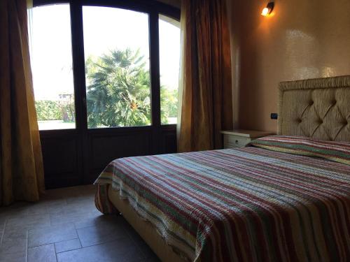 圣维托诺曼Borgo dei Normanni的一间卧室设有一张床,窗户拥有棕榈树