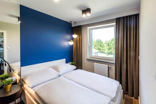 科沃布热格VacationClub – Porta Mare Baltica Apartament 8A的卧室配有白色的床和蓝色的墙壁