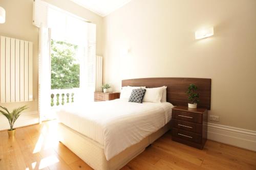 伦敦Queen Victoria Apartments的一间卧室设有一张大床和一个窗户。