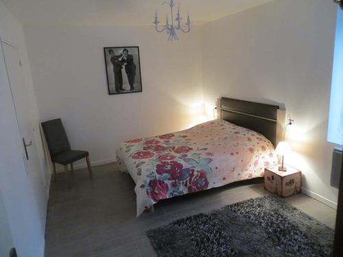 索米耶尔Les Studios-Hôtel de Sommières的一间卧室配有一张床、一盏灯和一把椅子