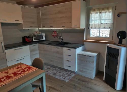 福尔马扎Fuchs Haus的厨房配有白色橱柜、桌子和微波炉