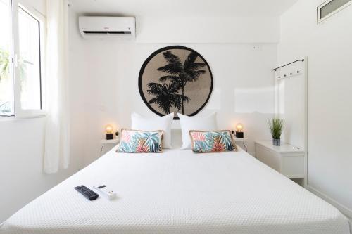 Anse Marcel Kaffa50 - Plage& 3Piscines - Anse Marcel的白色卧室设有一张白色大床,墙上挂着棕榈树