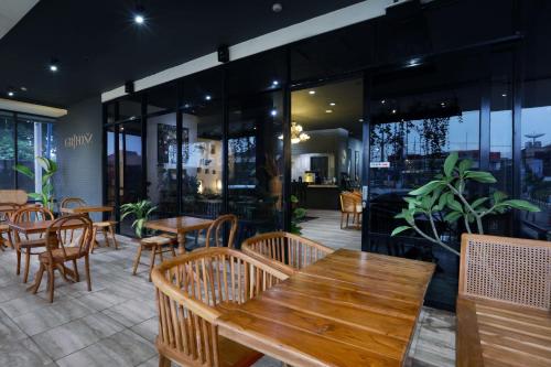 巨港Algoritma Hotel的餐厅设有木桌、椅子和窗户。