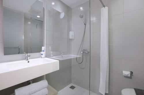 巨港Algoritma Hotel的白色的浴室设有水槽和淋浴。