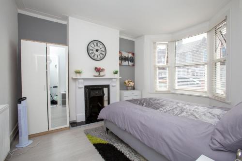 伦敦Dream Home Estate的卧室配有一张床,墙上挂着一个钟