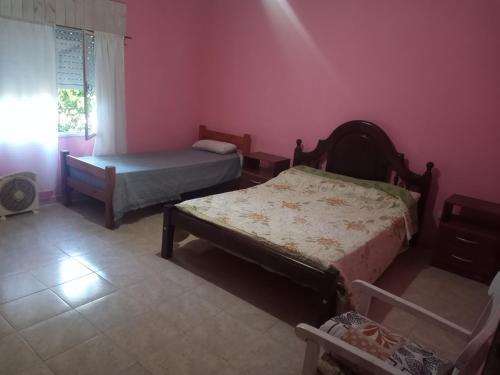 圣哈维尔Casa en Las Tapias cerca de Villa de Las Rosas的卧室配有两张床,位于带粉红色墙壁的房间