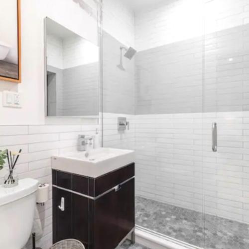 纽约Modern Holiday Apartment with Strategic Location in New York的一间带水槽和玻璃淋浴的浴室