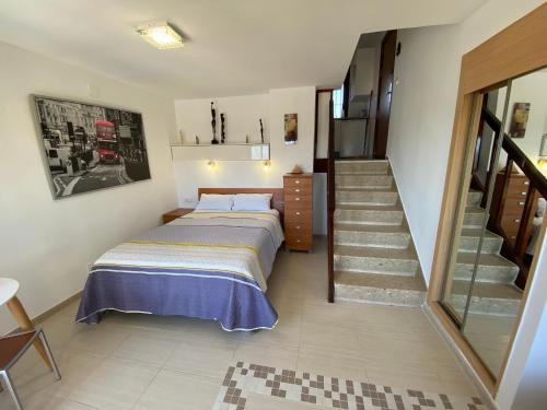 贝纳尔马德纳Benalmadena ALOHA PLAYA SEA VIEW LOFT的一间卧室设有一张床,楼梯位于卧室内