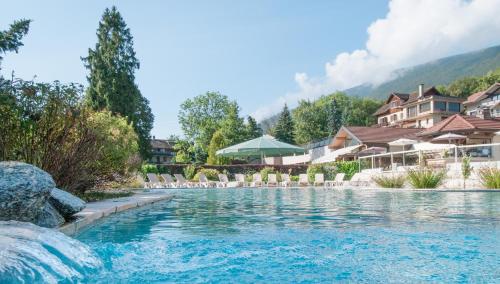 圣若里奥Residence Les Chataigniers的一个带椅子和建筑物的度假村游泳池