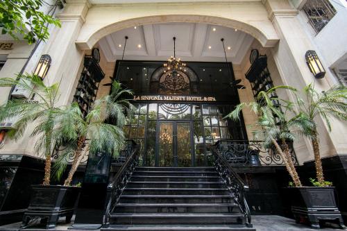 河内La Sinfonía Majesty Hotel and Spa的一座拥有楼梯和棕榈树的建筑的大堂