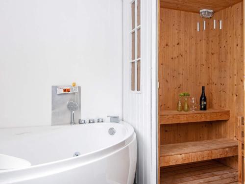 斯凯恩Holiday home Skjern XIX的浴室配有白色浴缸和木墙