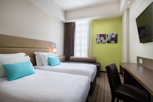 新加坡Hotel Traveltine的酒店客房配有两张床和一张书桌