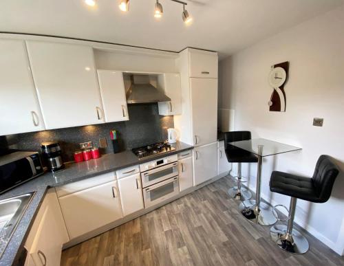 福尔柯克NEW Super 2 Bedroom Flat in Falkirk的厨房配有白色橱柜和带凳子的台面