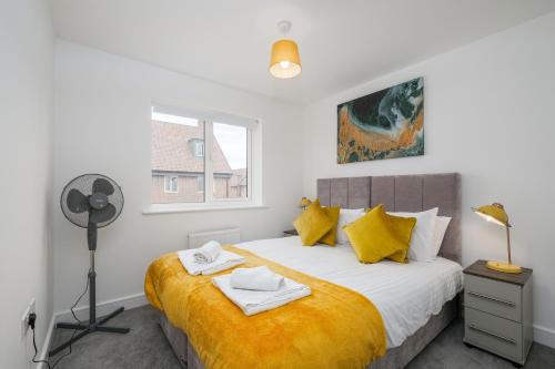 艾尔斯伯里Modern 5 Bedroom 3 Bathroom Serviced House Aylesbury with parking By 360Stays的一间卧室配有一张带黄色床单的床和一扇窗户。