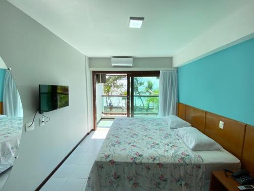 纳塔尔Araçá Praia Flat - Ponta Negra的一间卧室设有一张床、一台电视和一个窗口。
