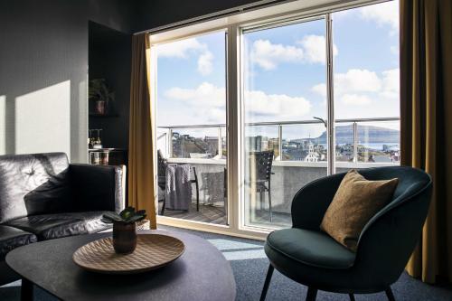托尔斯港62N Hotel - City Center的客厅配有椅子、桌子和大窗户