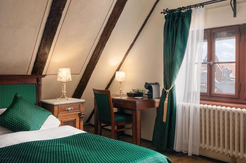 布拉格查尔斯酒店的一间卧室配有一张床、一张书桌和一个窗户。