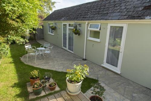 多切斯特Bramlies Bed & Breakfast的一座种植了盆栽植物的房屋的后院和一座庭院