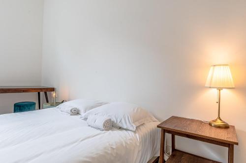 泰昂维Le Grain de Sable的卧室配有一张白色的床、桌子和台灯
