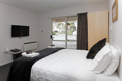 基督城尔舒酒店阿马尔菲汽车旅舍的卧室设有一张白色大床和一扇窗户。