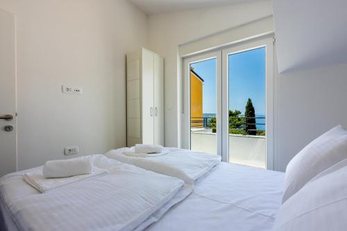 塞尔瑟Luxury Apartments Lovorka 3 & 4***/****的白色客房的两张床,设有大窗户