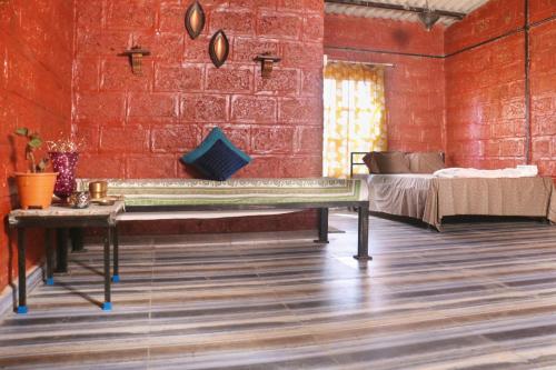 纳西克SiddhaDham - Farm Stay Cottage 1的红砖房,配有长凳和床