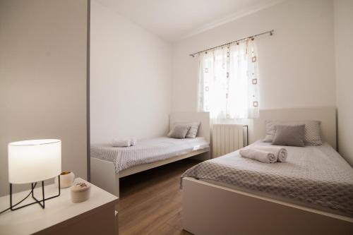波尔Apartments Teskera的白色卧室配有两张床和一盏灯