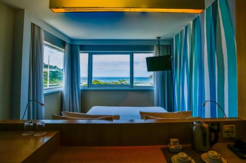 里约热内卢Mercure Rio de Janeiro Barra da Tijuca的客房设有一张床和一个享有海景的窗户。
