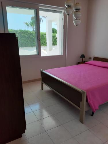 普拉A 30 metri dal mare di Nora, casa confortevole的卧室配有粉红色的床和窗户。