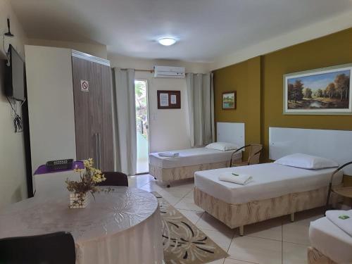 马卡埃Pousada Alto Riviera的酒店客房设有两张床和一张桌子。