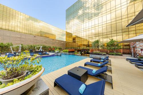 马尼拉Hyatt Regency Manila City of Dreams的酒店大楼前的游泳池配有蓝色躺椅